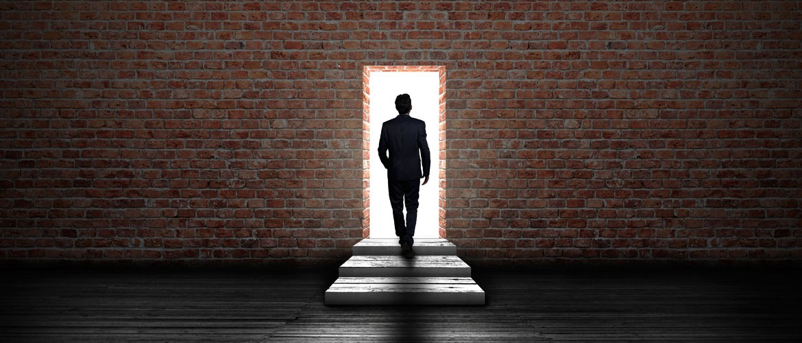 Businessman passing through a doorway in a brick wall